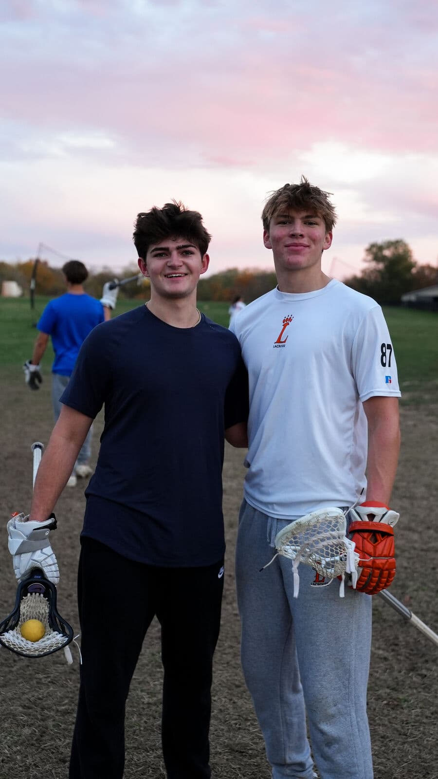 Two athletes with sticks at sunset